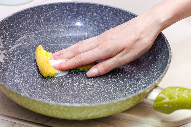 Drain most of the soapy water and use a soft-bristle cleaning brush